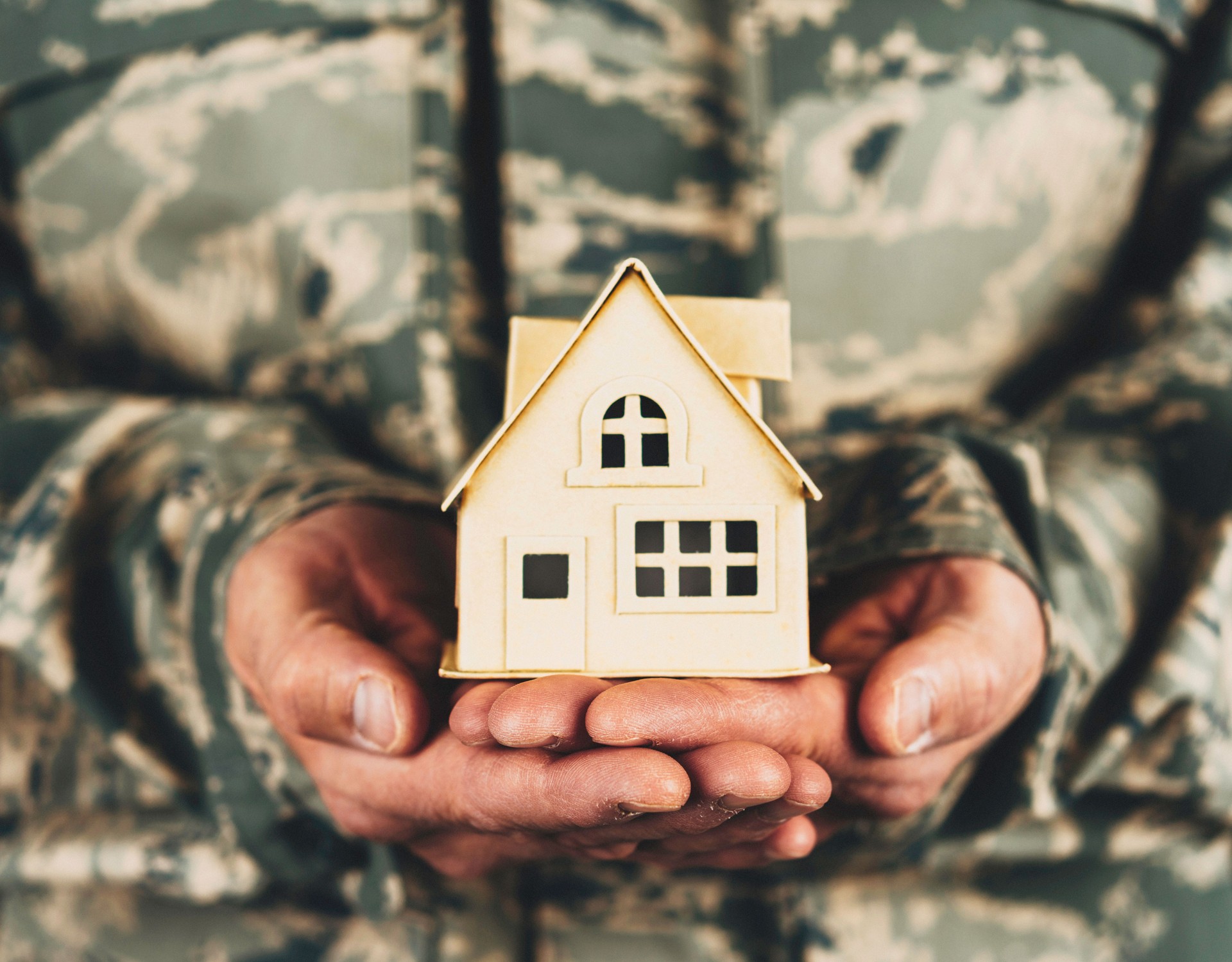 Military service member holding little cardboard house